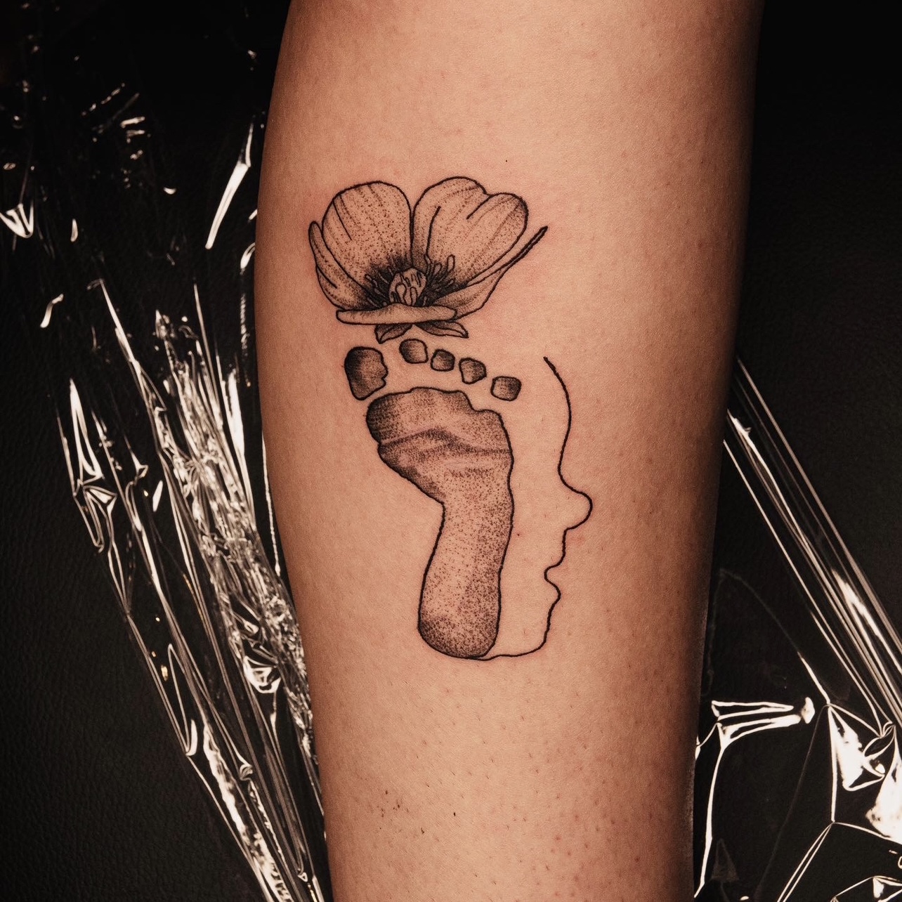 Read: Baby Face Profile with Footprint and Flower Leg Tattoo